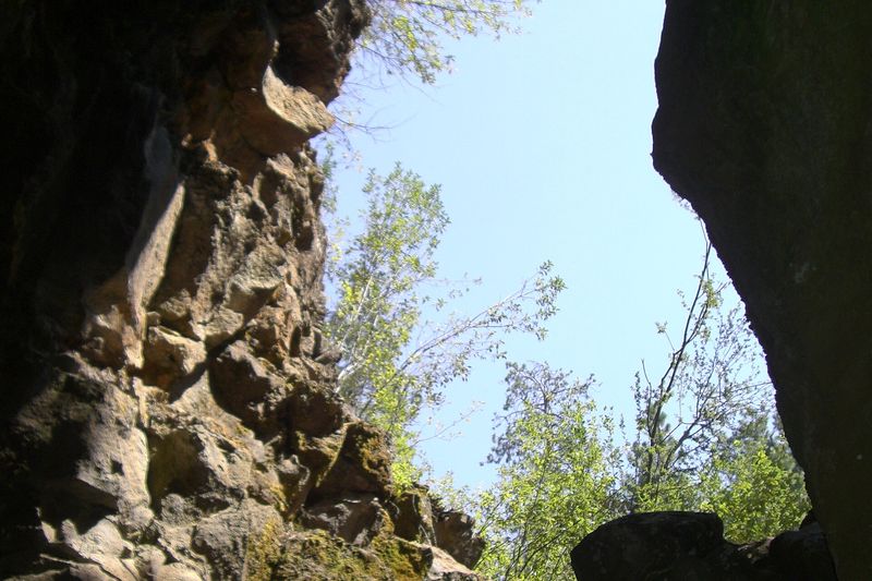 Looking up from inside Lava River Cave toward daylight and trees at the entrance