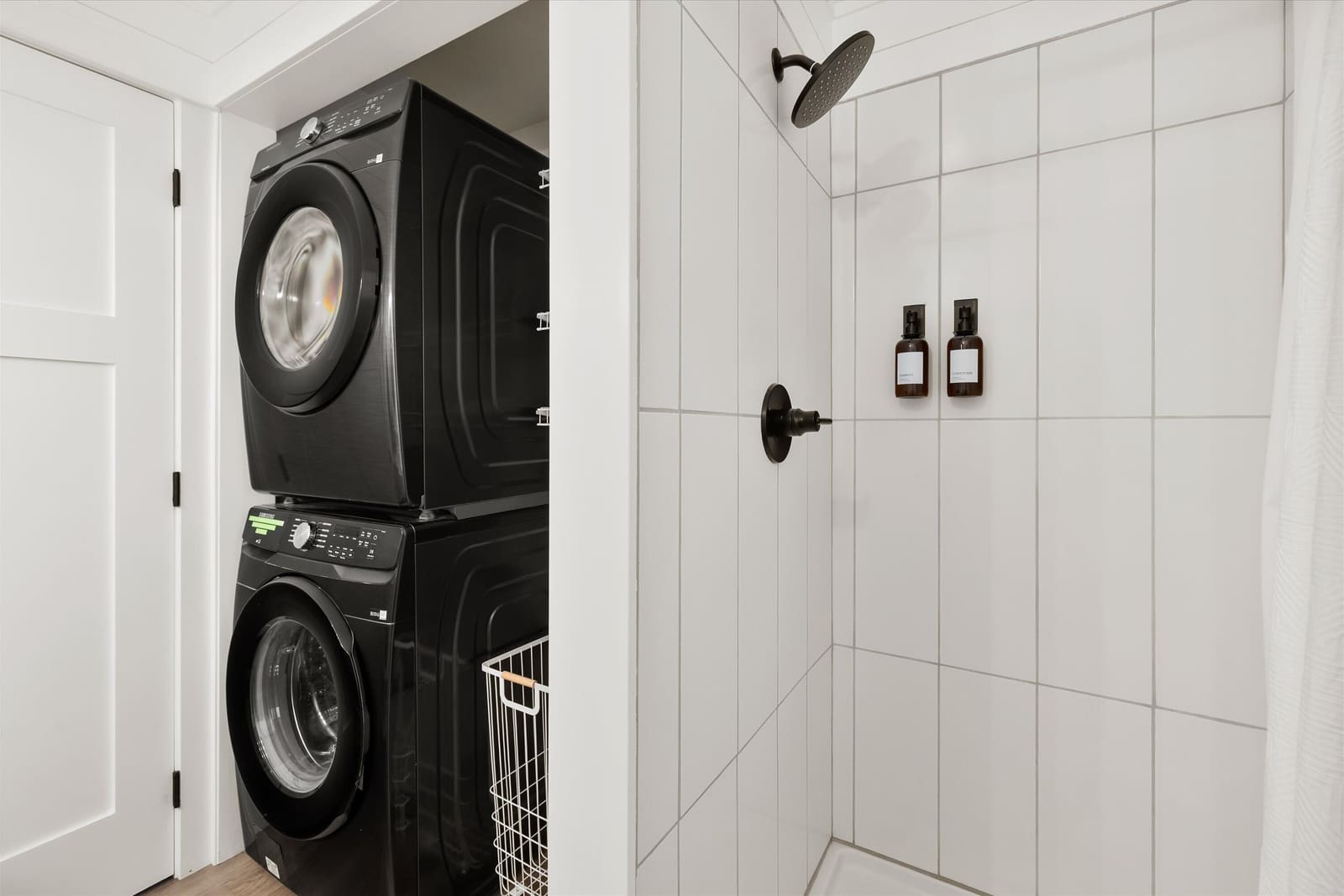 In-unit stacked washer and dryer beside the tiled walk-in shower