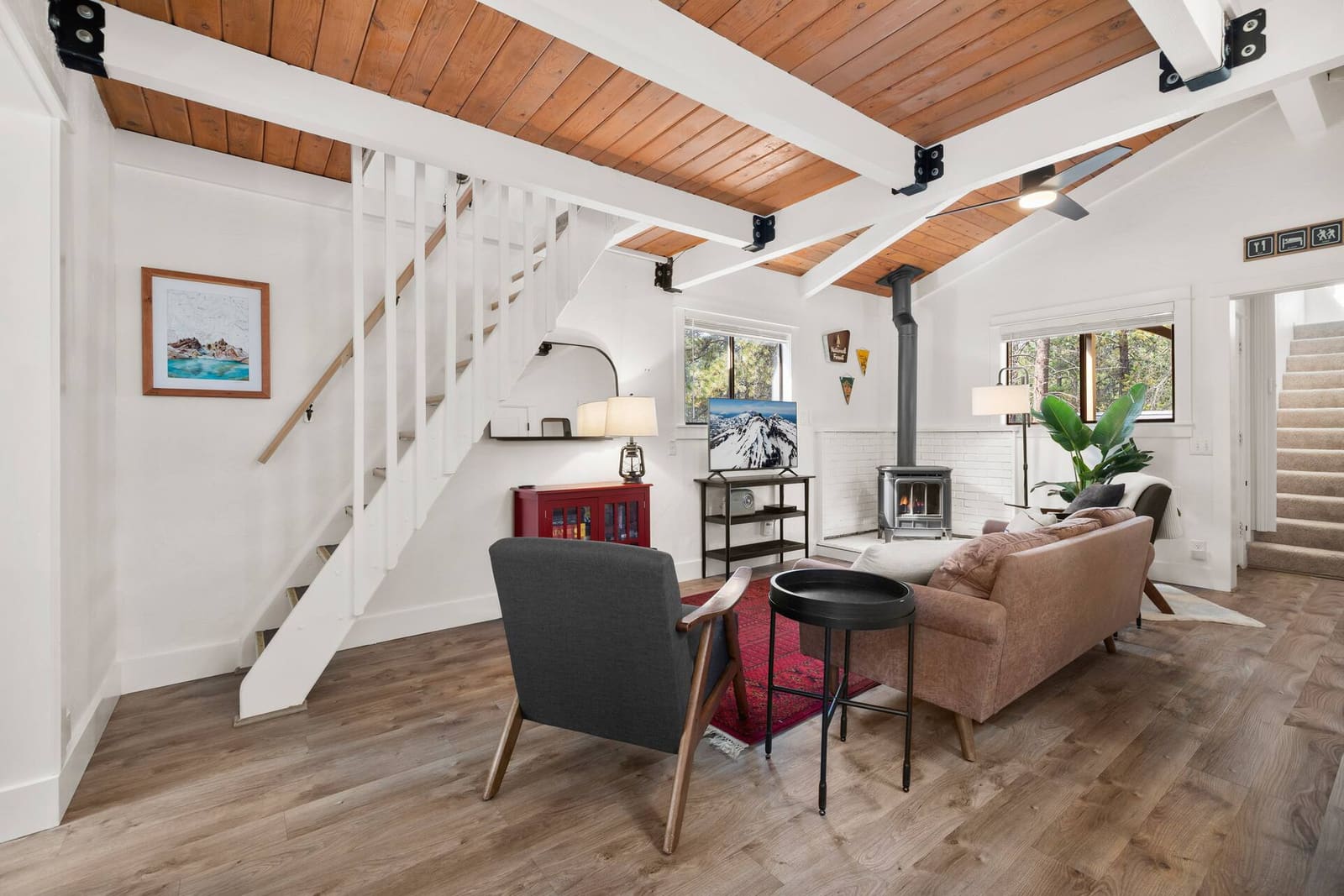 Living room seating beside the staircase, with ski artwork and pine views through the window